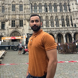 Moo in an orange polo on a city square