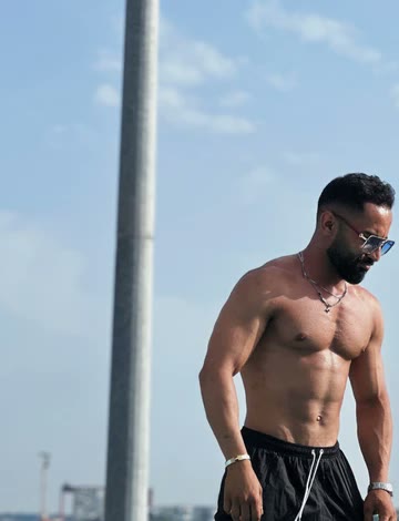 Moo shirtless on a sunny rooftop in sunglasses